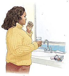 Mujer de pie en el lavabo del baño que toma la píldora anticonceptiva.