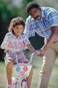 Imagen de un padre enseñando a su hija a andar en bicicleta