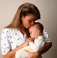 Fotografía de una madre besando a su bebé en la frente