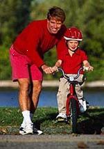 Imagen de un padre enseñando a su hijo a andar en bicicleta
