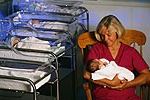Fotografía de una enfermera con un bebé en la guardería del hospital
