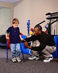 Fotografía de un niño pequeño con muletas, durante una sesión de terapia física