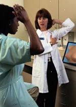Fotografía de una médico enseñándole a su paciente cómo realizar un autoexamen de la mama
